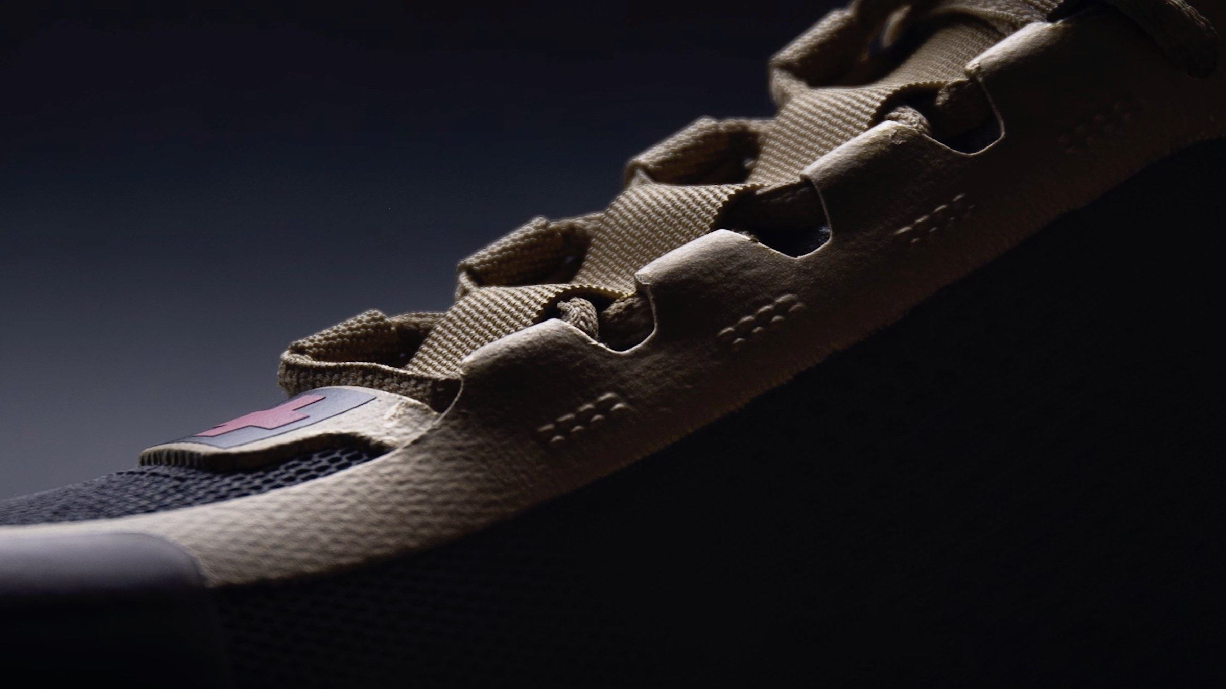 Close-up of the black and gold shoe's tan lace cage over black knit.