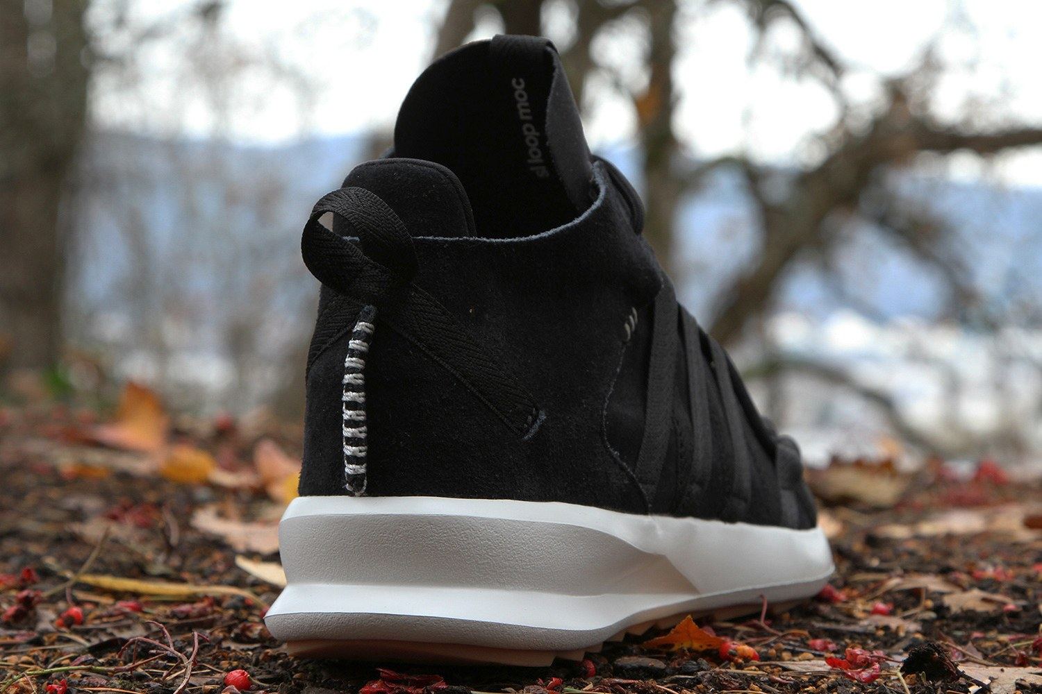 The black shoe from the back three-quarter, with a heel pull loop and a white stitched heel seam.
