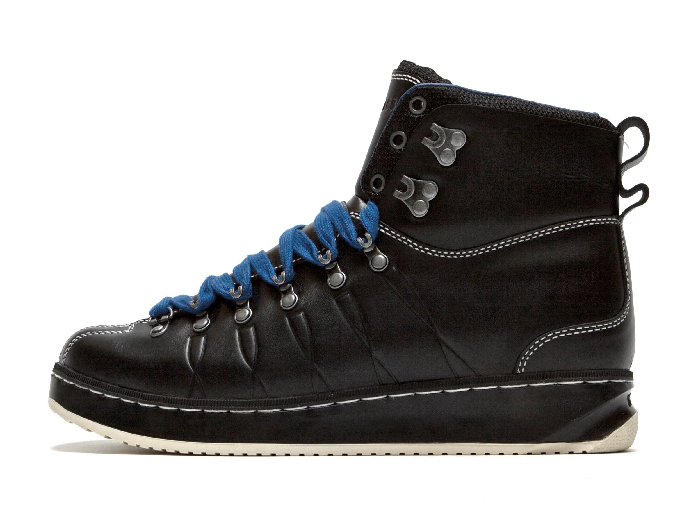 The black Alpine Classic Boot from the side, with contrast stitching, blue laces and a tan sole edge.