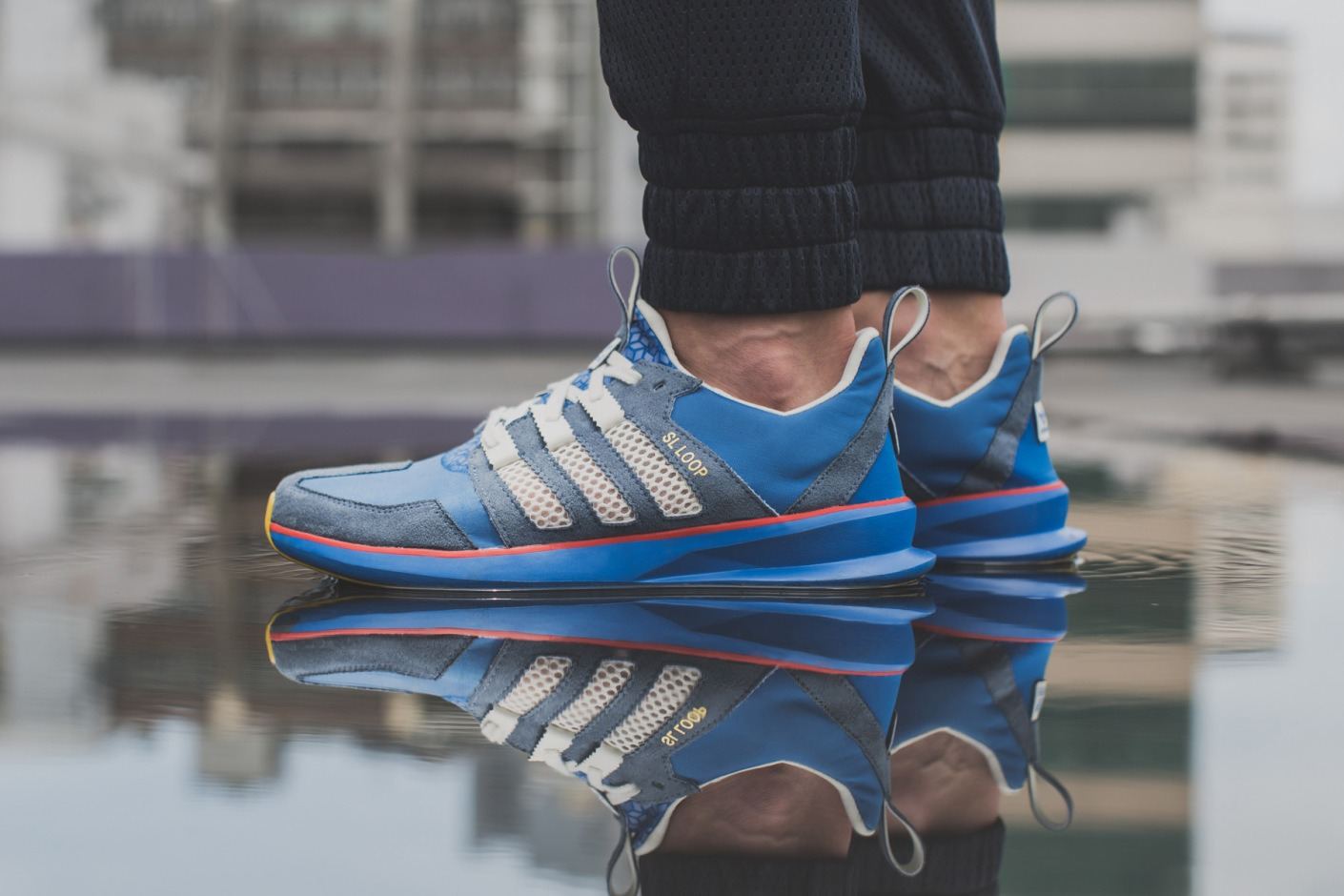 The blue suede pair worn at the edge of a puddle, reflected in the water.