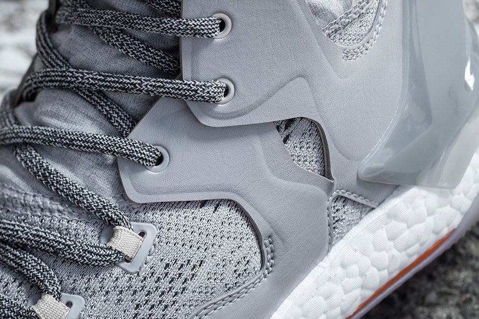 Close-up of the grey knit collar, translucent midfoot wrap and lace loops above white Boost.
