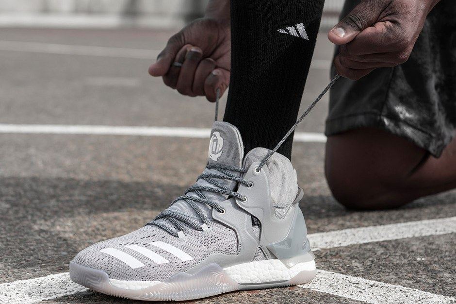 A player lacing up the grey D Rose 7 on an outdoor court.