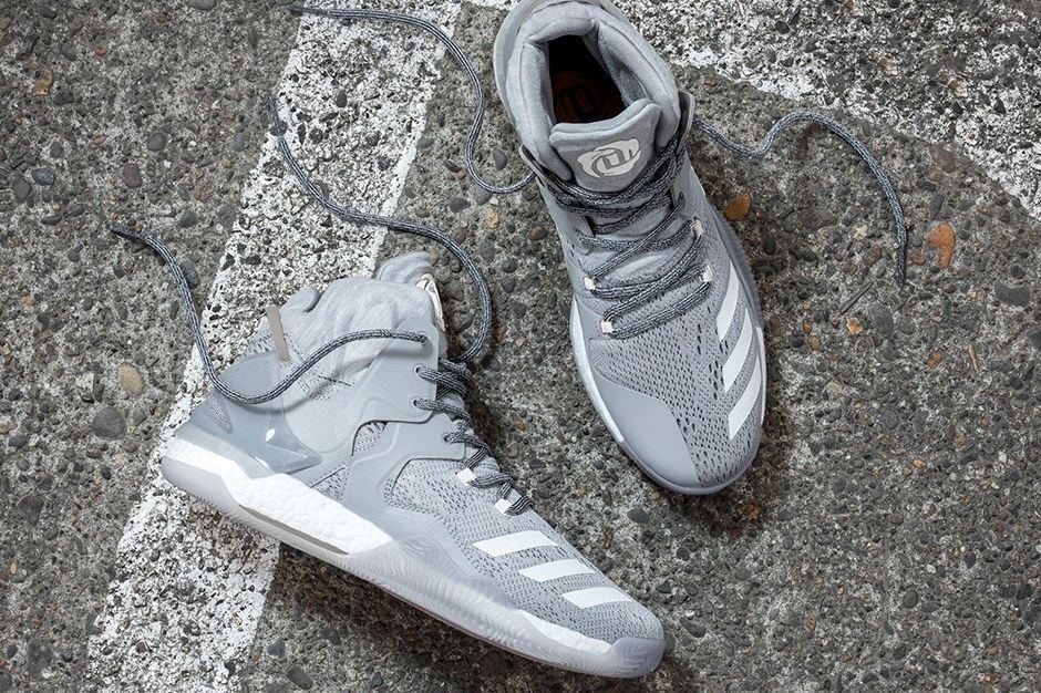 A pair of grey D Rose 7s on asphalt, with white stripes and grey laces.