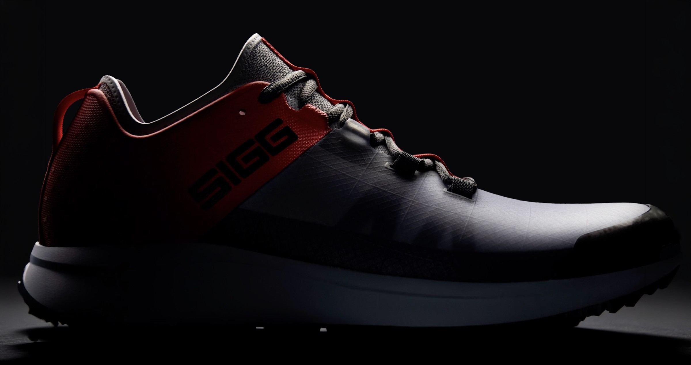 3D rendering of the shoe in grey ripstop with a red heel and SIGG wordmark, lateral view in low light.