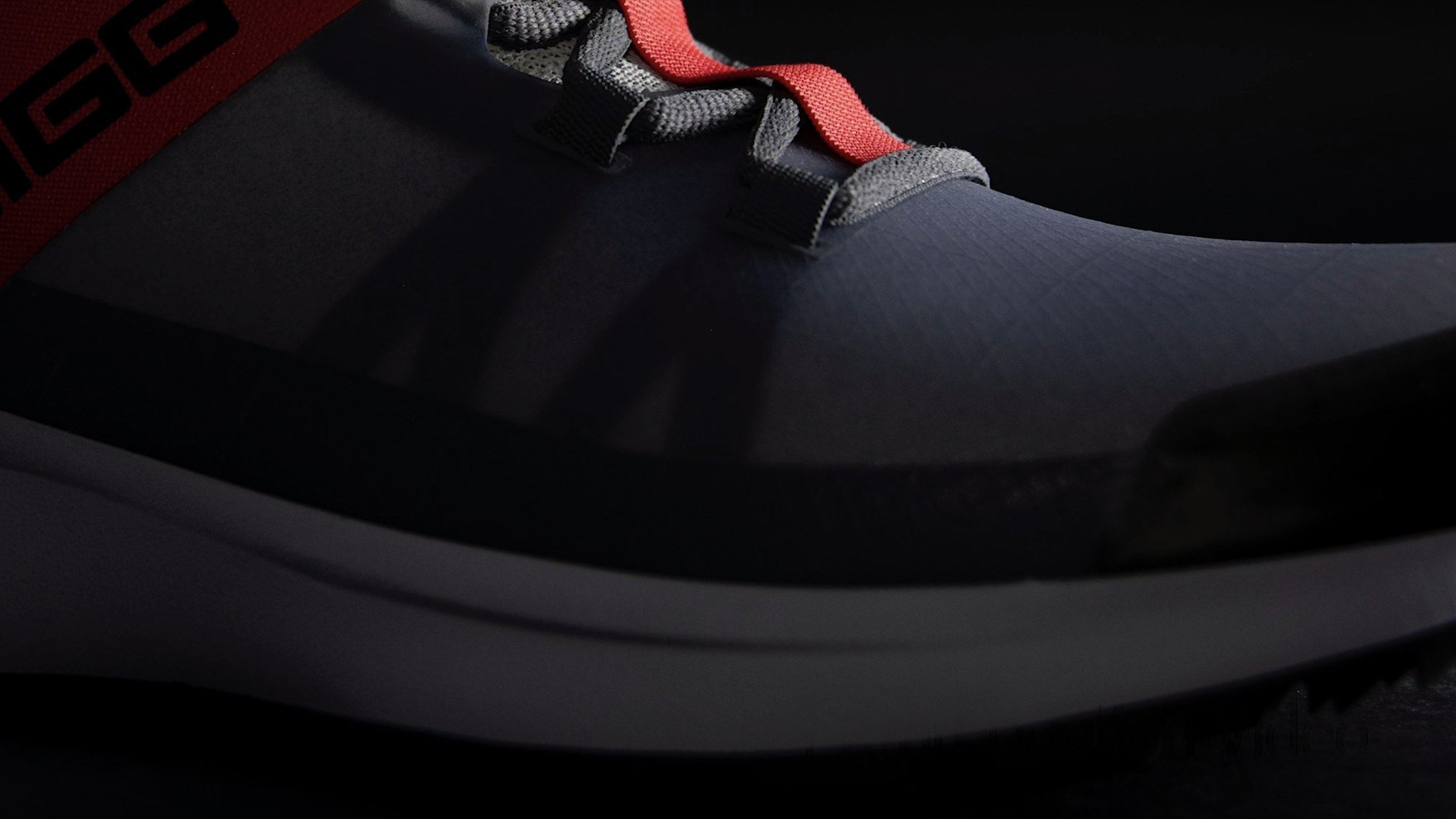 Close-up of the grey and red shoe at the toe, in grey ripstop with a red lace loop.