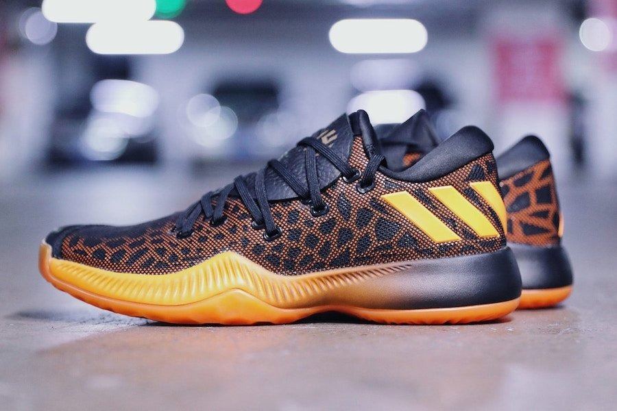 Harden BTE in black with an orange cheetah-print upper, orange stripes and a translucent orange outsole, lateral view in a parking garage.