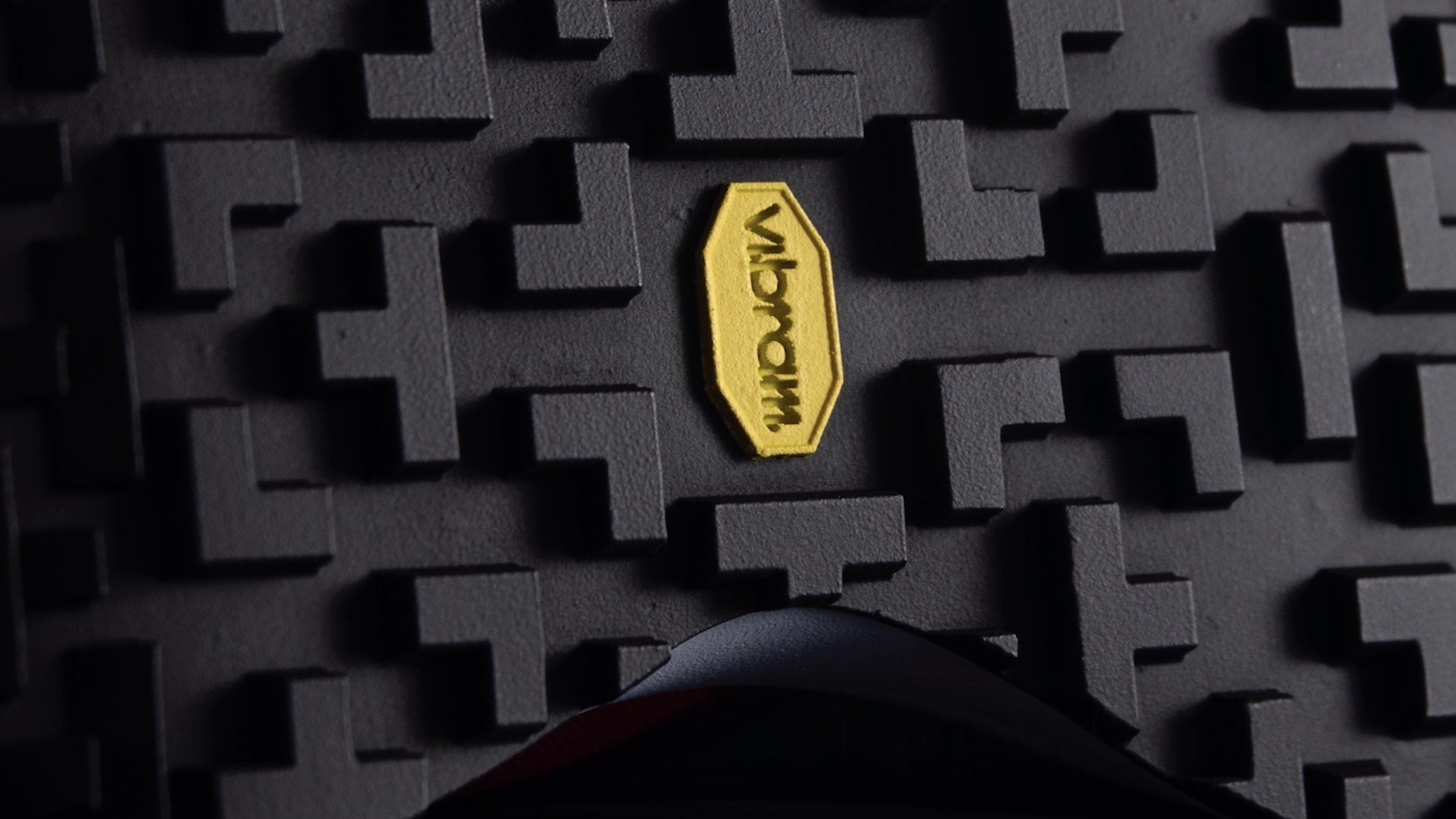 Close-up of a dark grey outsole with Swiss cross lugs and a yellow Vibram badge.