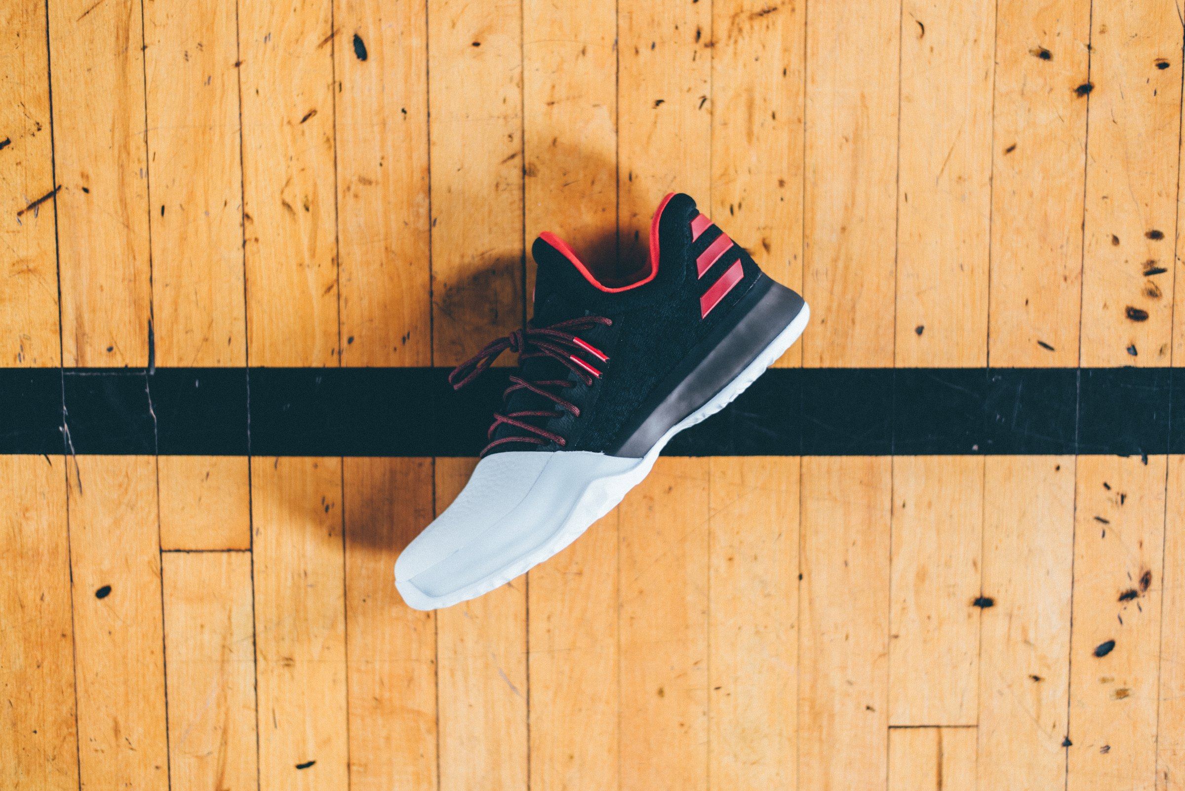 Overhead view of the shoe on a hardwood court across a painted line.