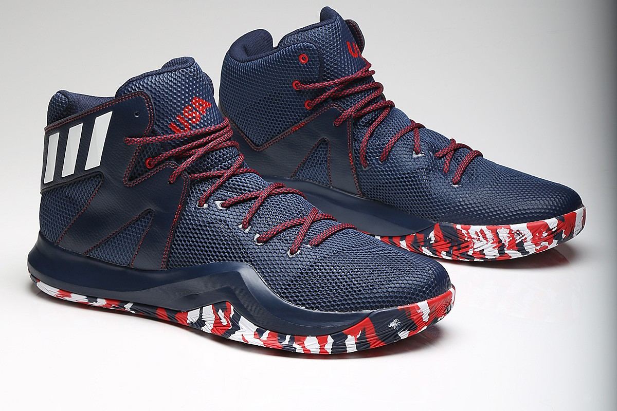 A pair of Crazy Bounce in navy with white stripes, red laces, and camo outsoles on a grey studio backdrop.