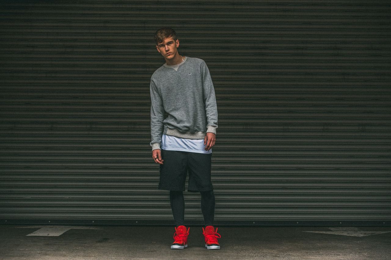 A man in front of a roller shutter wearing a grey sweatshirt, black shorts and the red C-10.