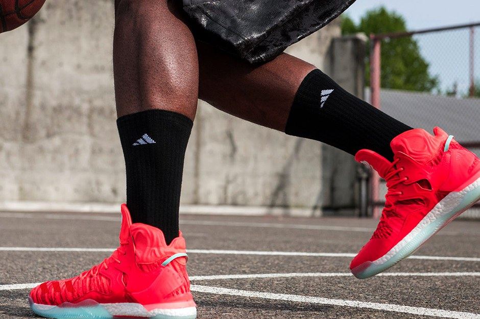 The red D Rose 7 on foot on an outdoor court, with black socks.