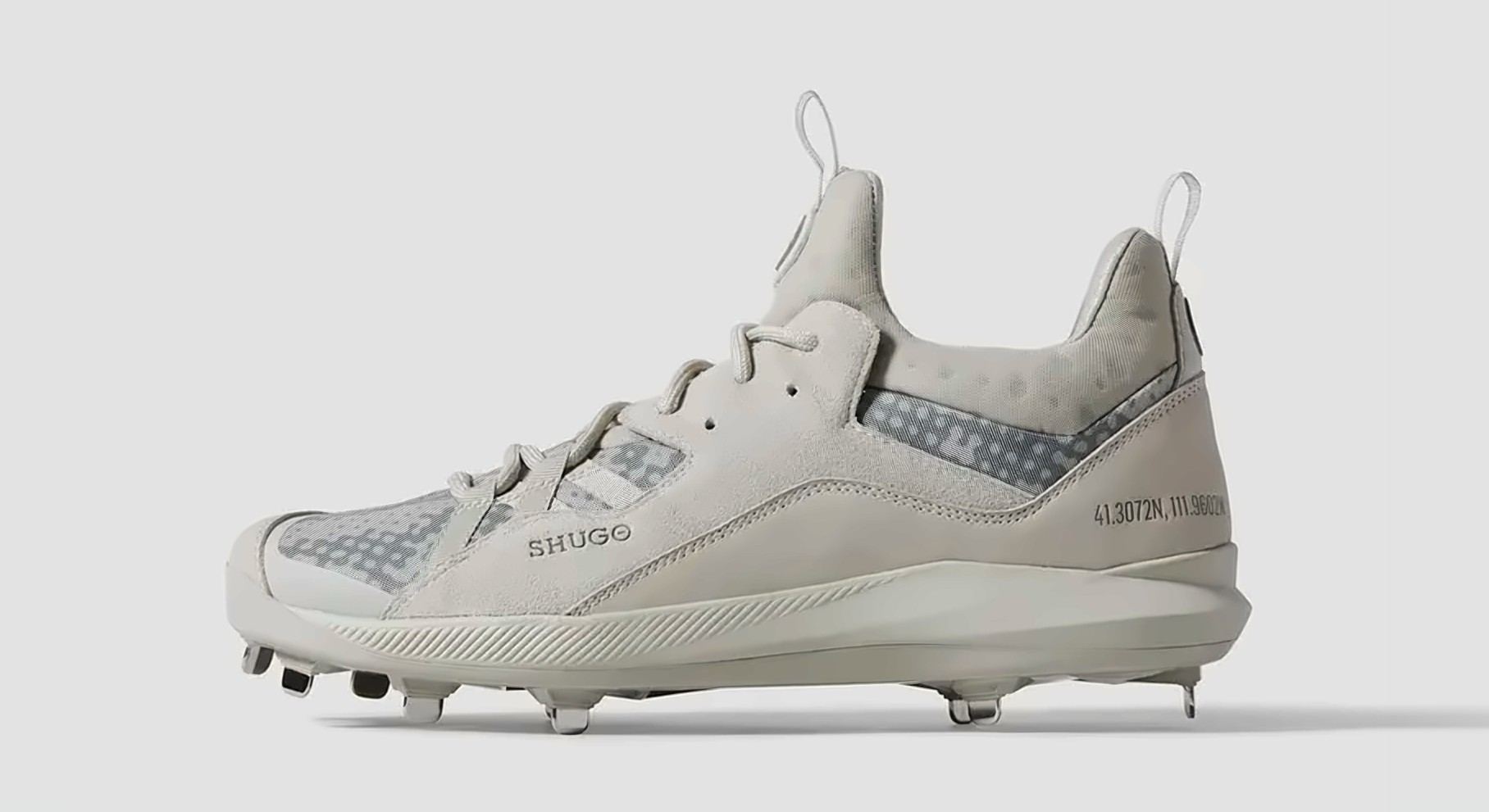 The Zero in cream with a grey camo mesh panel, a SHUGO wordmark on the quarter, and coordinates printed at the heel, lateral side view.
