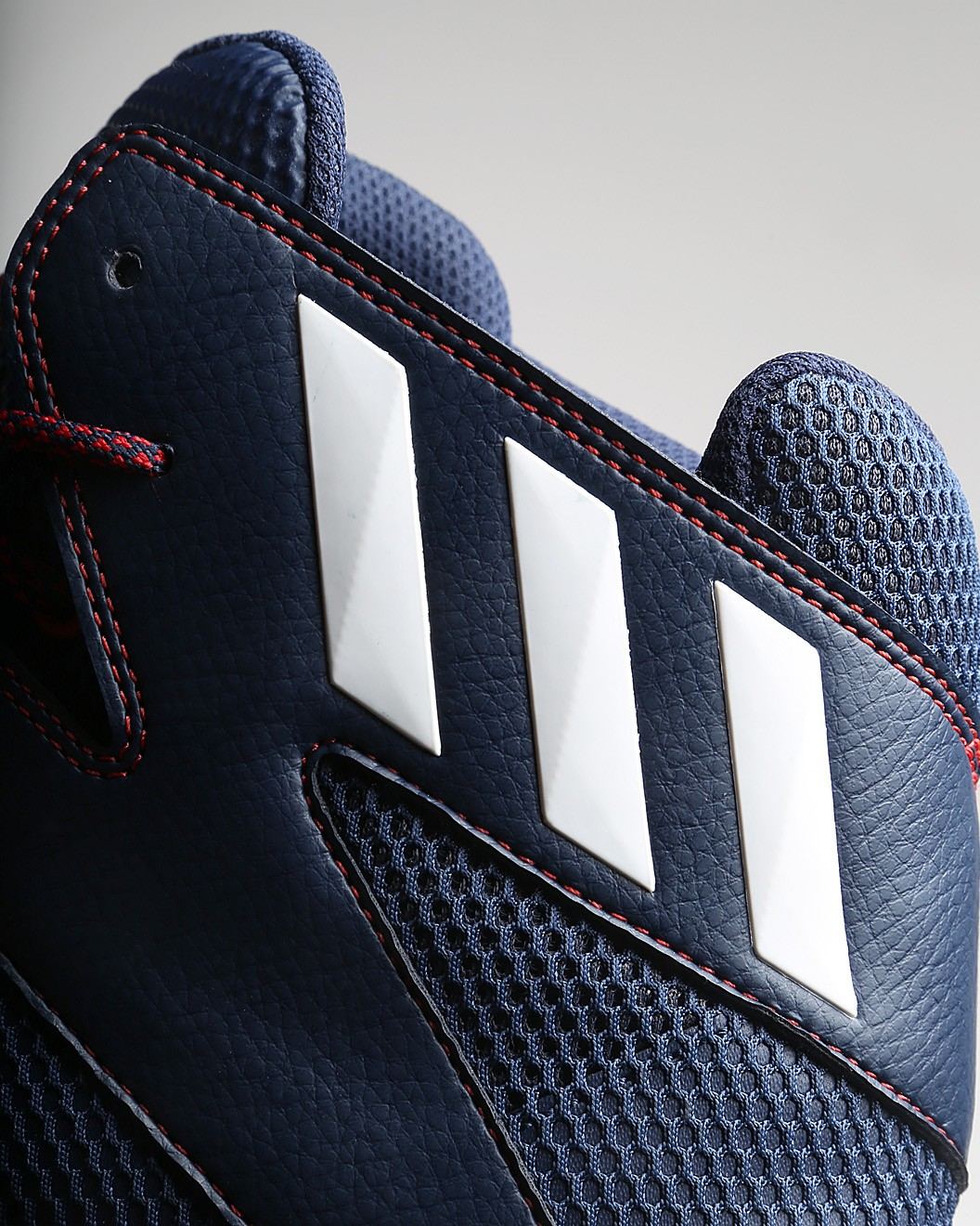 Close-up of three white stripes on the navy heel overlay with red stitching.