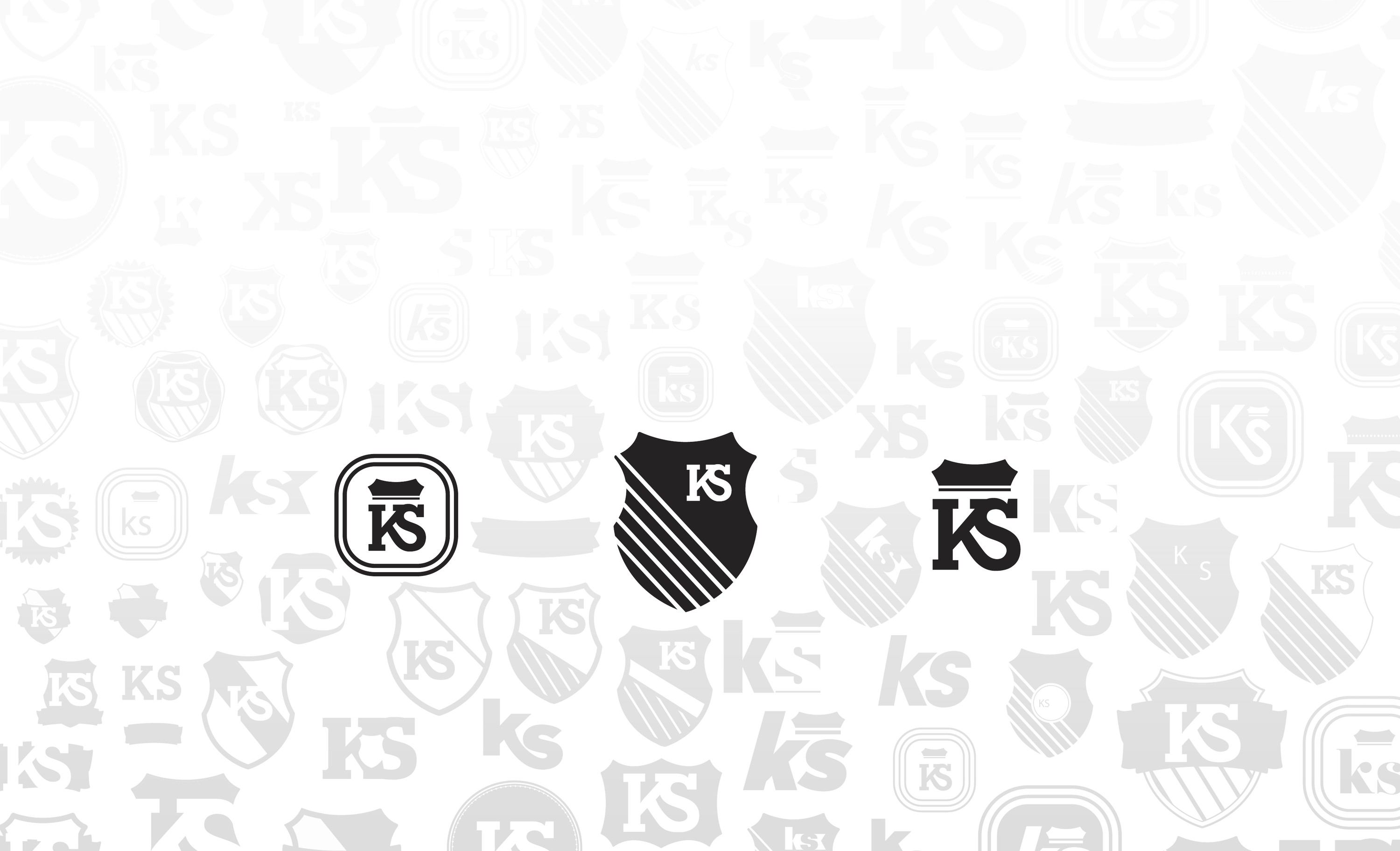 Three KS logo directions, a badge, a striped shield and a crowned wordmark, over a grey field of earlier logo explorations.
