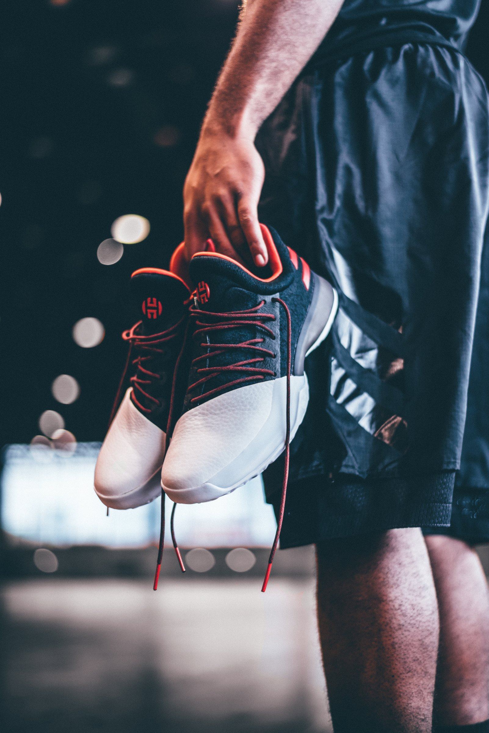 A pair of Harden Vol. 1 carried by the laces on a court.