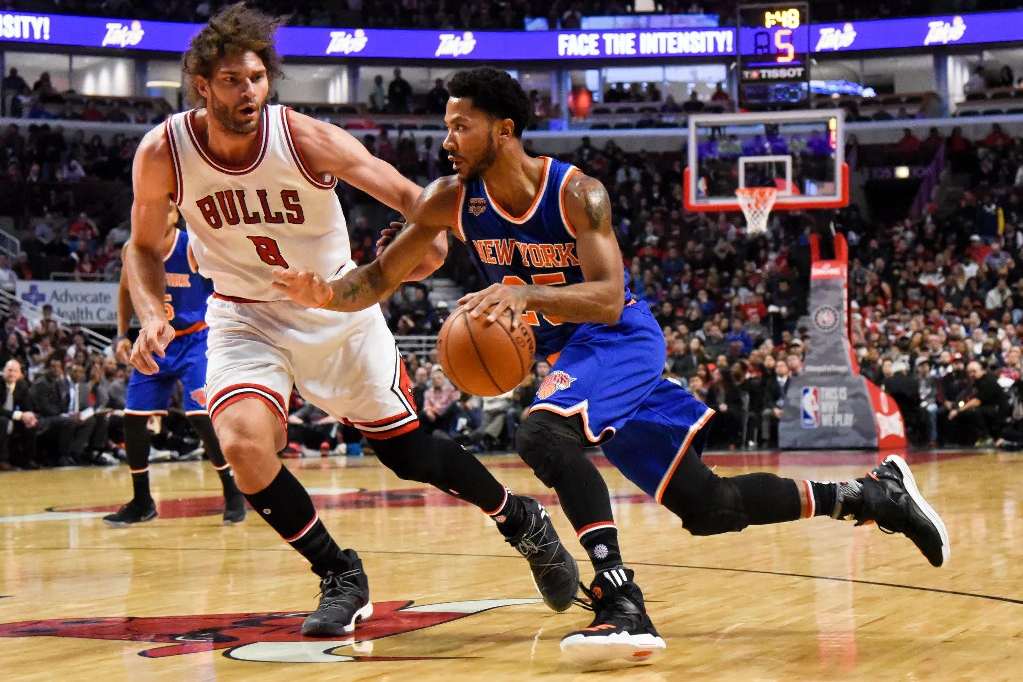 Derrick Rose in a New York Knicks uniform driving past a Chicago Bulls defender in a game.