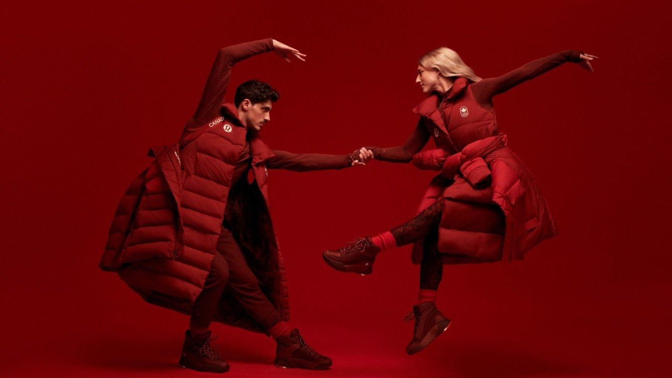Two athletes in red Team Canada puffer coats dancing against a red backdrop, wearing the red opening ceremony boots.