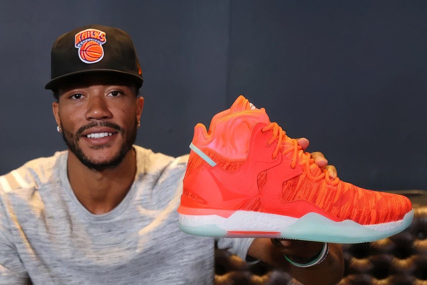 Derrick Rose in a Knicks cap holding up the orange D Rose 7.