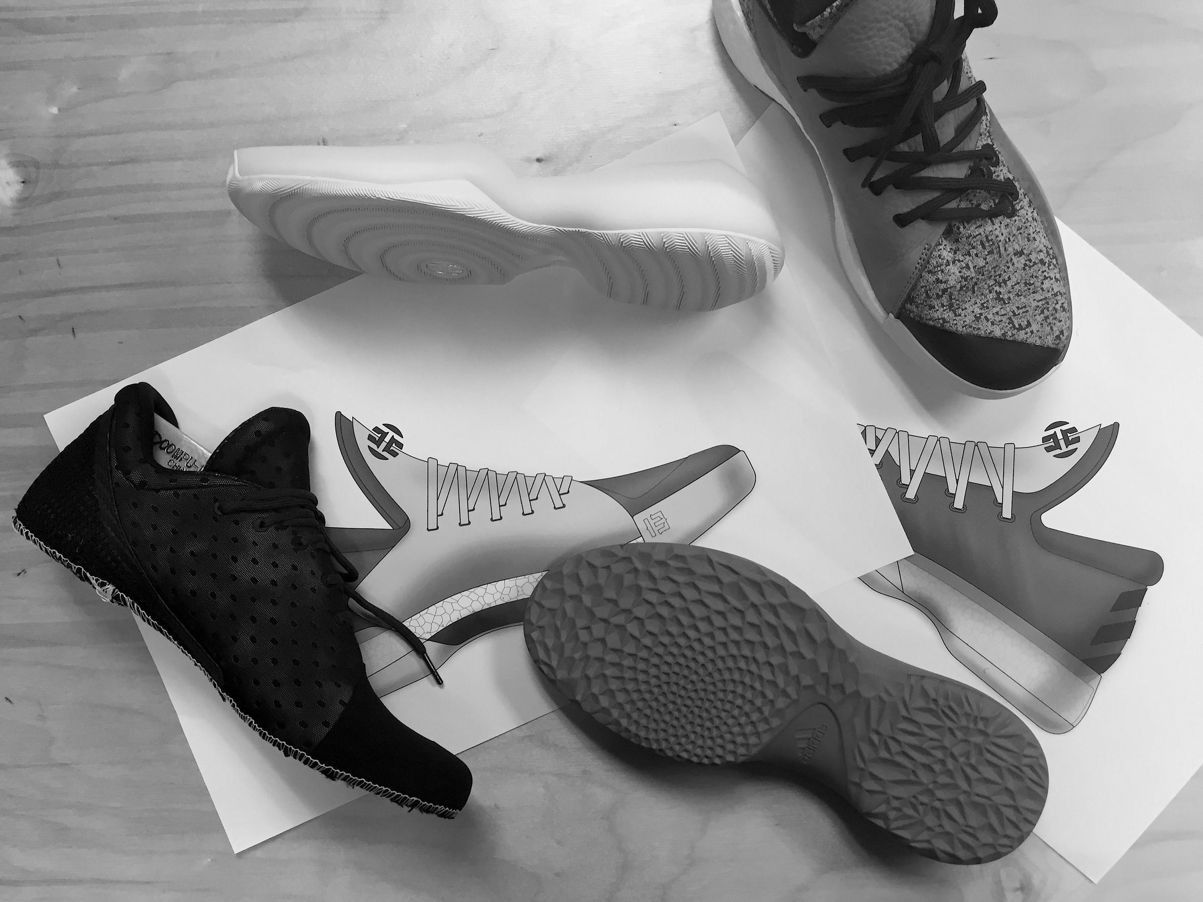 Black-and-white photo of Harden BTE parts on a table, with an upper sample, outsole samples, and printed renderings of both options.